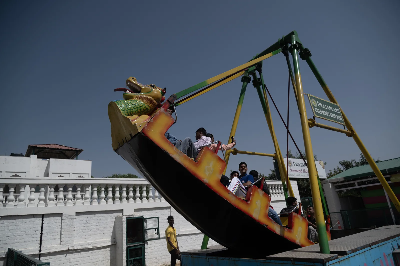 Families riding a painted dragon ship swinging high above the carnival zone at Pratapgarh Farms